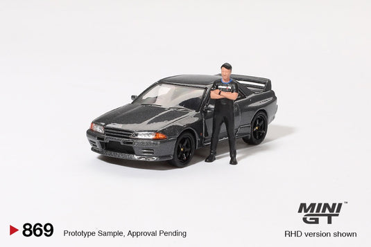 NISSAN SKYLINE GT-R (R32) NISMO NISMO GUNMETAL AVEC FIGURINE TSUGIO MATSUDA 1992 MINI GT 1:64
